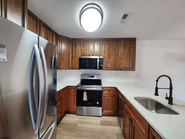 a kitchen with stainless steel appliances granite countertop a refrigerator a stove a sink and a window