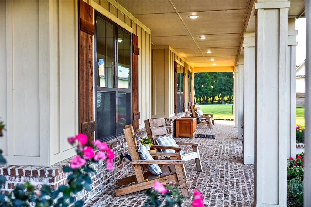 985 Vest Lane Pilot Point, TX 76258 - Photo 11 of 40 Expansive covered porch featuring a herringbone brick floor, board-and-batten siding, substantial support columns, recessed ceiling lighting, and dark-framed windows with wood shutters