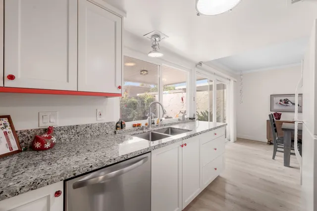 a kitchen with stainless steel appliances granite countertop a sink dishwasher and cabinets with wooden floor