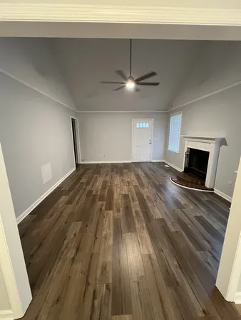 a view of empty room with wooden floor ceiling fan and window