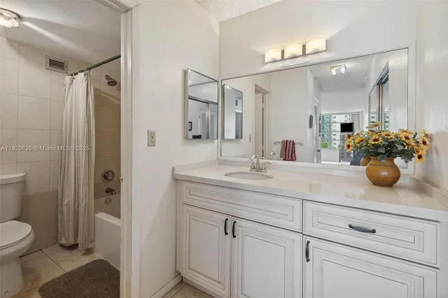 a bathroom with a granite countertop sink a toilet and shower