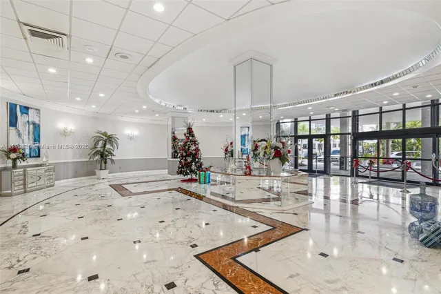 a room with lots of white furniture a chandelier and a view of living room