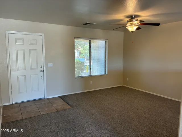 an empty room with windows and fan