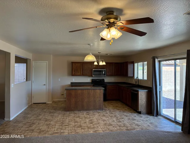 an empty room with a chandelier fan and wooden floor