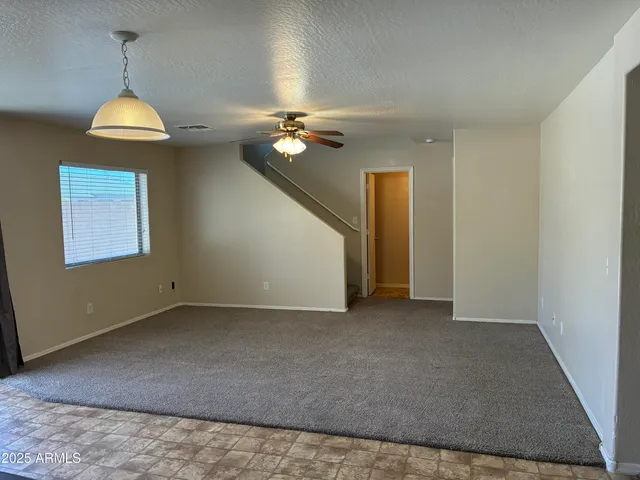 an empty room with a chandelier fan and a ceiling fan