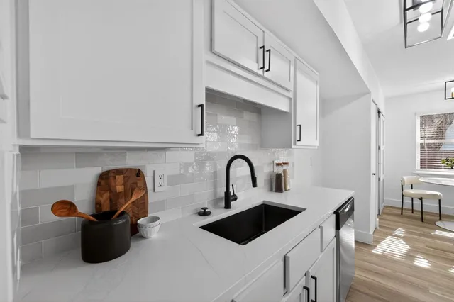 a kitchen with a sink a stove and white cabinet with a dining table