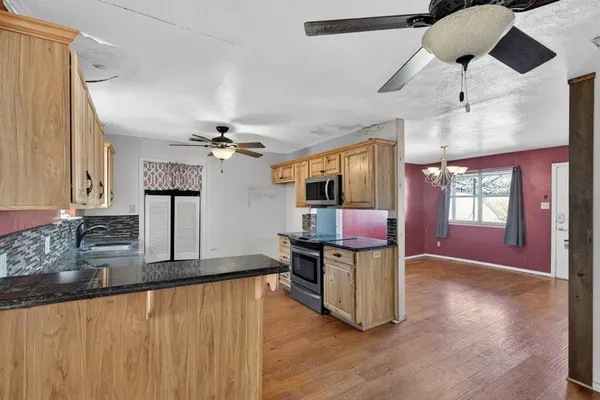 a view of a kitchen with stainless steel appliances wooden floor and chandelier