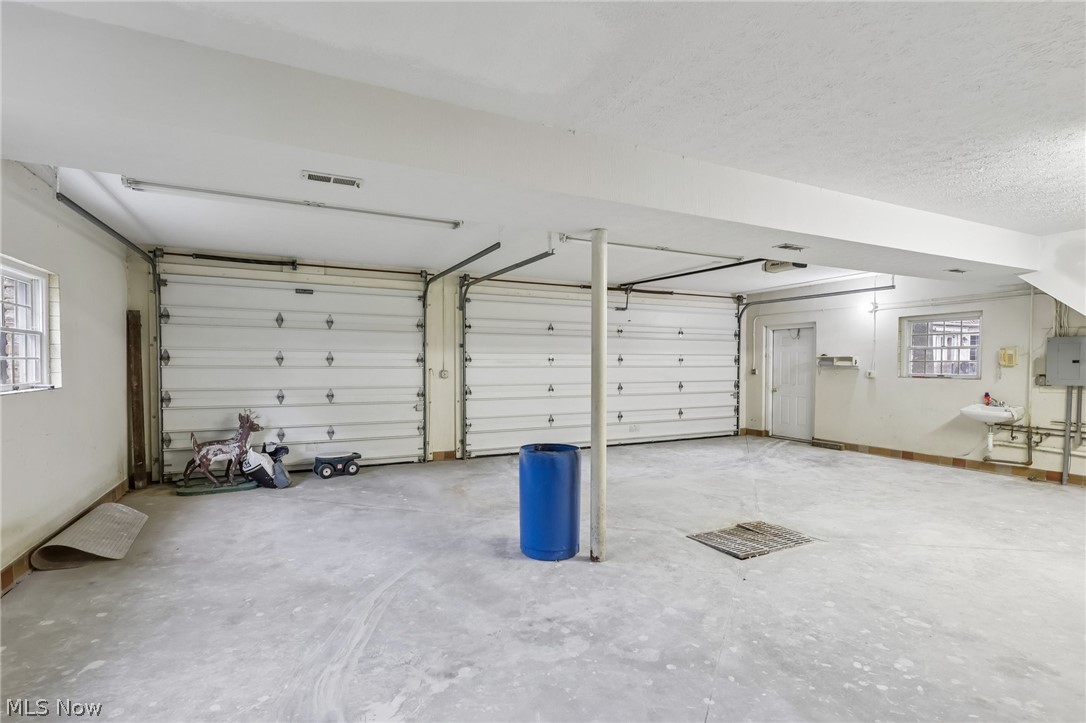 4551 Shaw Road Akron, OH 44333 - Photo 24 of 36 Spacious garage featuring two overhead doors, concrete flooring, ample lighting, a utility sink, and multiple windows