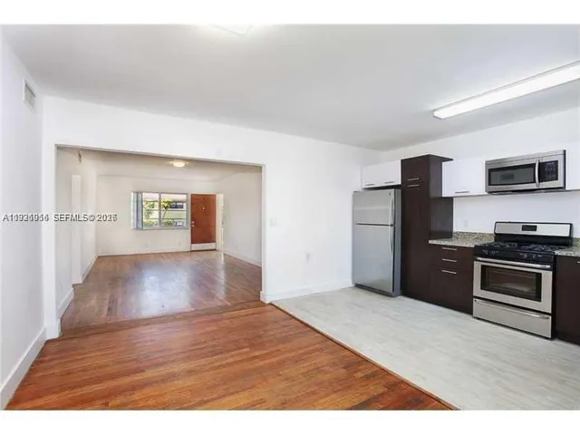 a view of a kitchen with a sink stove cabinets and empty room