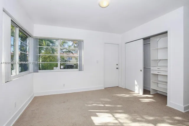 a view of an empty room with a window and cabinet