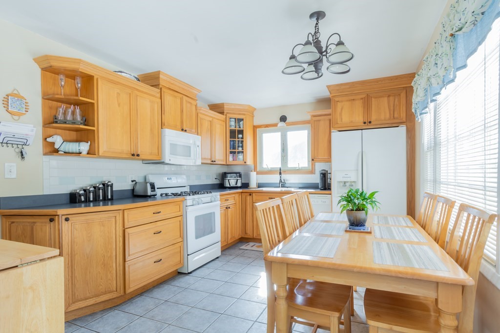 115 Ridgewood Road New Bedford, MA 02745 - Photo 17 of 28 a kitchen with stainless steel appliances kitchen island granite countertop a table chairs in it and wooden floors