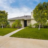 a view of a white house next to a yard with big trees