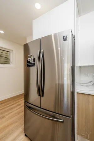 a view of a refrigerator in kitchen and white cabinets
