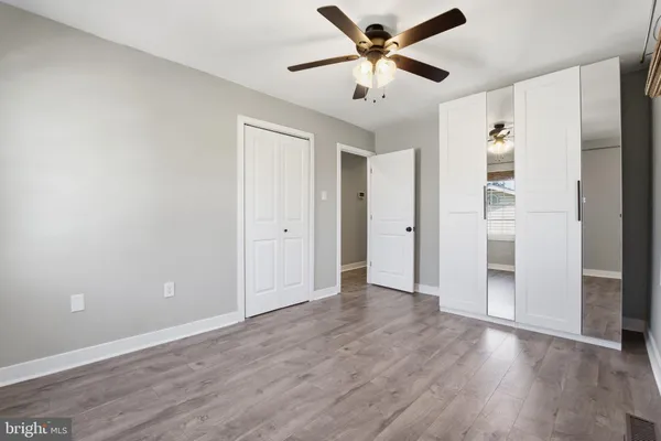 an empty room with wooden floor and ceiling fan