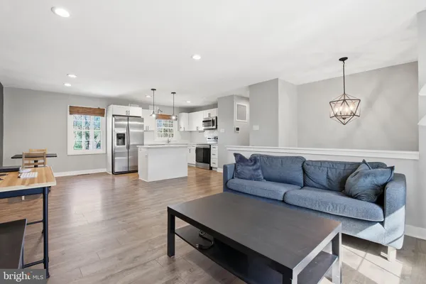 a living room with furniture kitchen view and a wooden floor