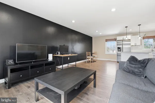 a living room with stainless steel appliances furniture and a flat screen tv