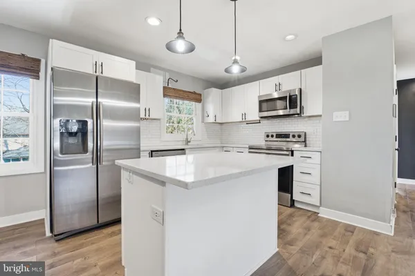 a kitchen with kitchen island white cabinets and stainless steel appliances