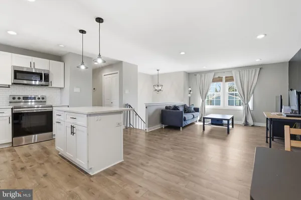 a kitchen with stainless steel appliances granite countertop a stove top oven a sink dishwasher and a refrigerator with wooden floor