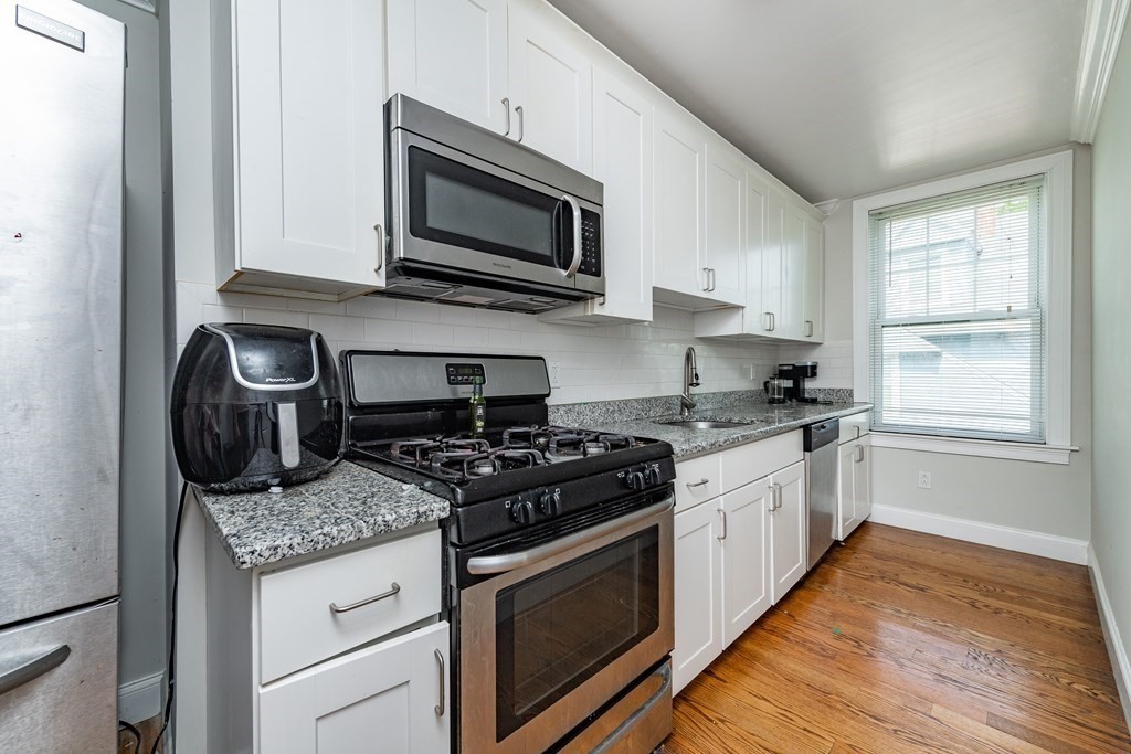 50-52 Townsend Street Boston, MA 02119 - Photo 12 of 15 a kitchen with granite countertop stainless steel appliances a sink cabinets and a window