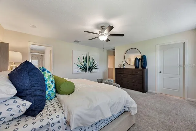 a spacious bedroom with a bed a dresser and a chandelier