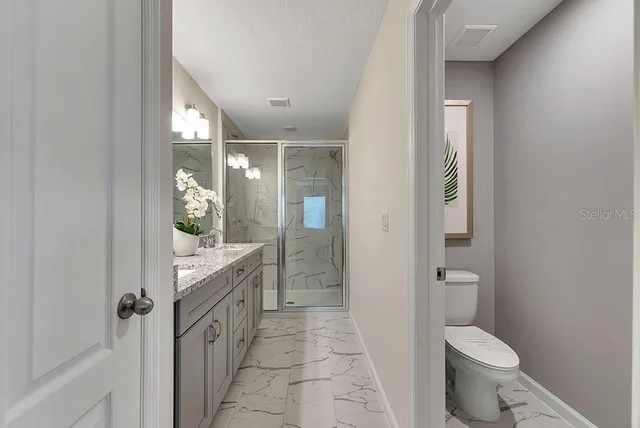 a bathroom with a granite countertop toilet and a shower