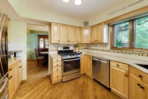 a kitchen with stainless steel appliances granite countertop a stove a sink dishwasher and a refrigerator with wooden floor