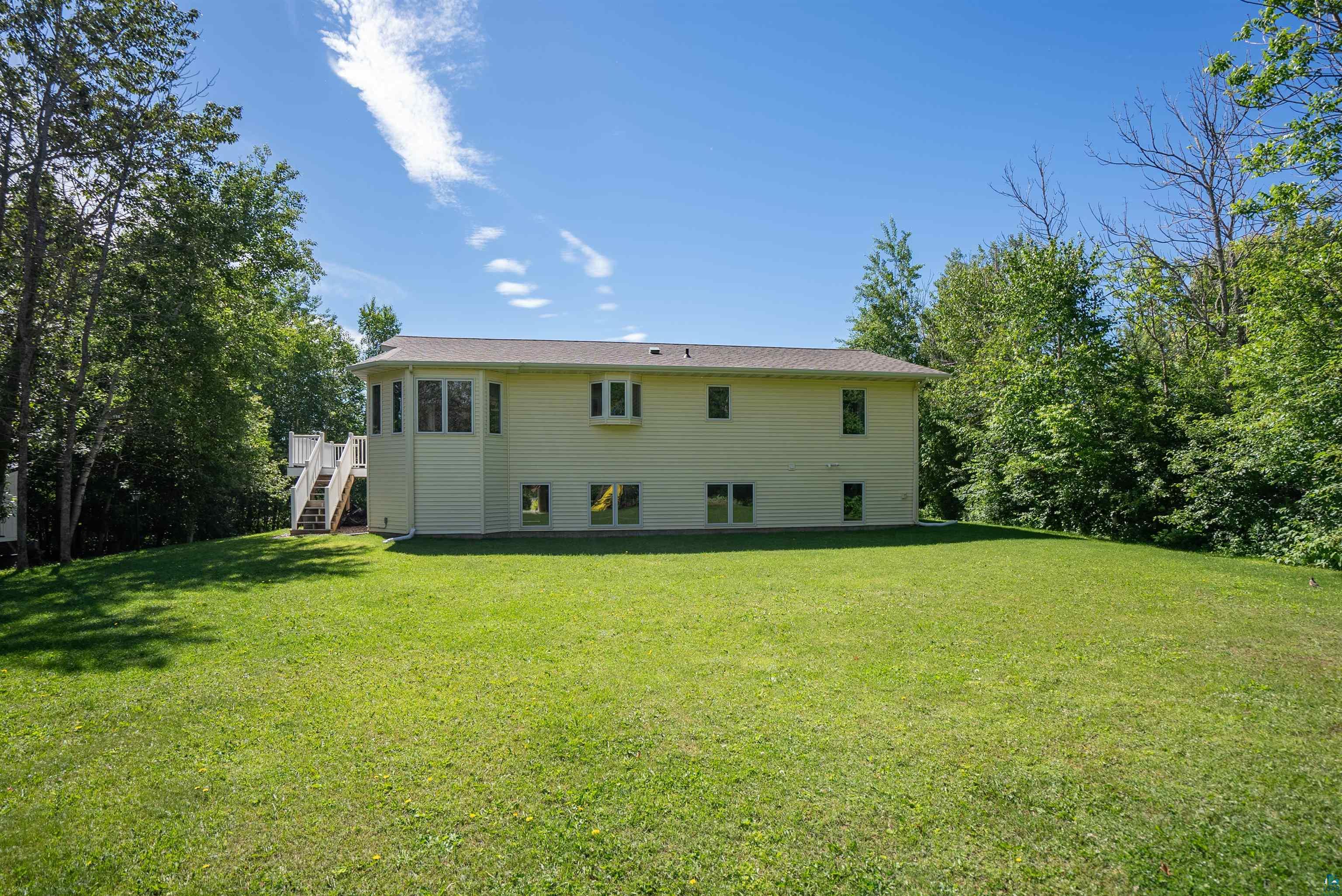 4809 Oak Ridge Drive Hermantown, MN 55811 - Photo 56 of 67 Expansive grassy yard surrounding a light-colored two-story residence with a multi-level deck and mature trees bordering the property