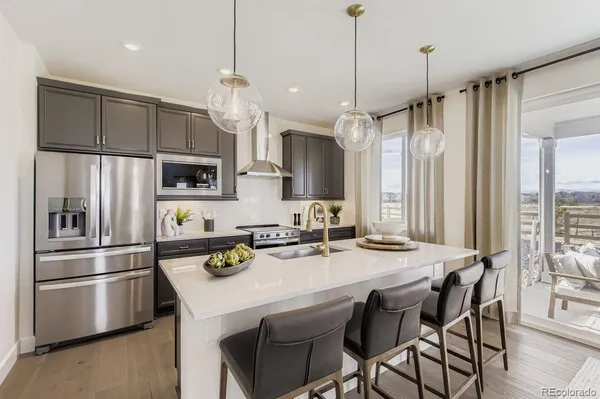 a kitchen with stainless steel appliances a stove a sink a refrigerator a center island a table and chairs