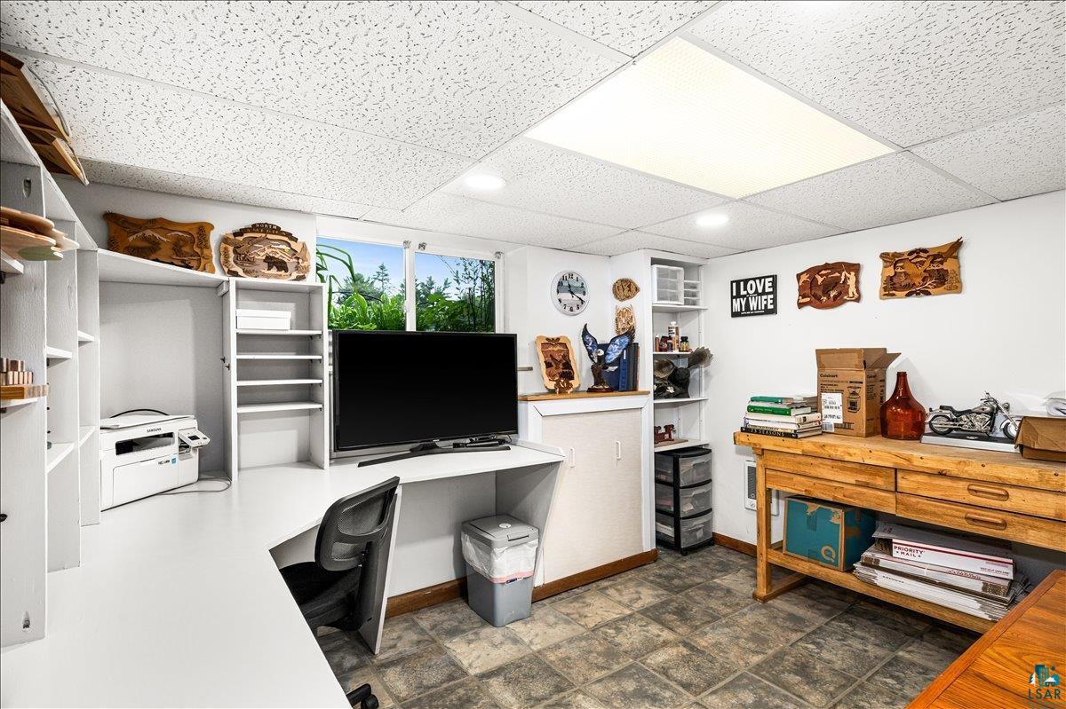 130 West Austin Street Duluth, MN 55803 - Photo 20 of 35 Versatile room featuring extensive built-in shelving, a dedicated workspace with a white desk, ample natural light from exterior windows, recessed lighting, and a textured drop ceiling