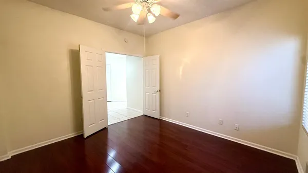 an empty room with wooden floor and a ceiling fan