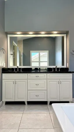 a close view of a sink a mirror and cabinets