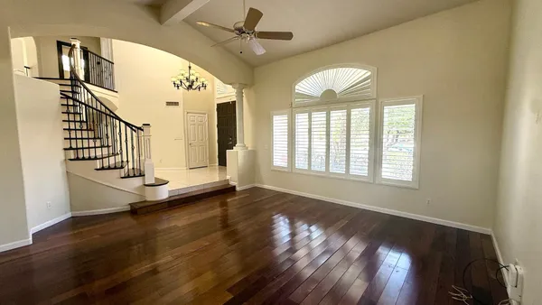 an empty room with wooden floor fan and windows