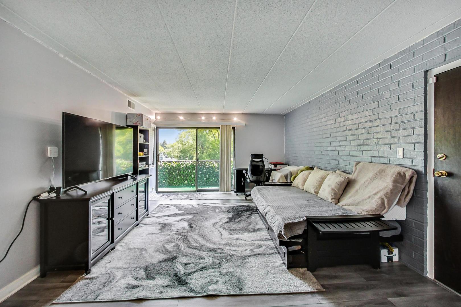 550 Timber Ridge Drive, Unit 304 Carol Stream, IL 60188 - Photo 5 of 22 a living room with furniture a flat screen tv and a floor to ceiling window