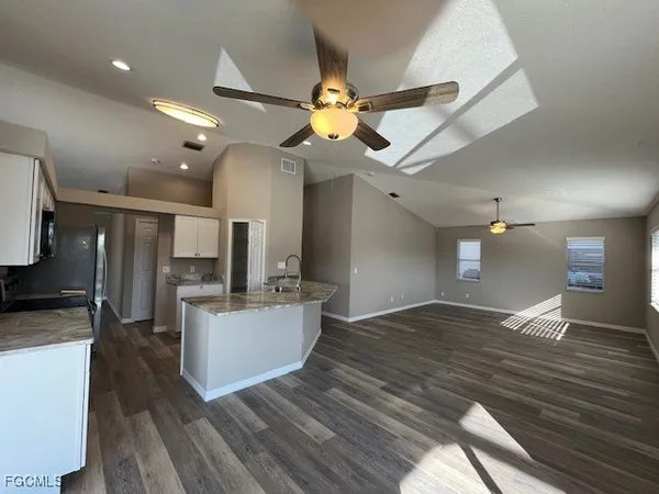 a view of a kitchen with a sink dishwasher a refrigerator with wooden floor and a fireplace