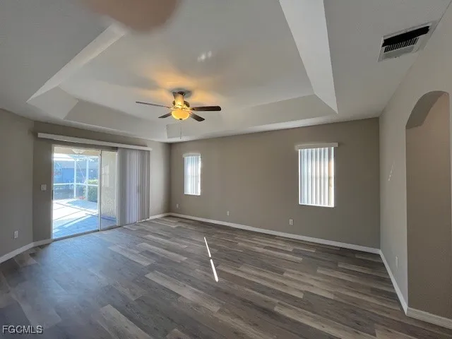 a view of an empty room with a window and wooden floor