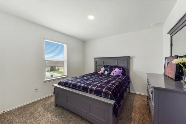 a bedroom with a bed and a flat tv screen on a dresser