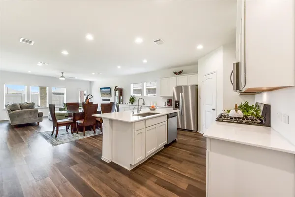 a large white kitchen with lots of counter top space and stainless steel appliances