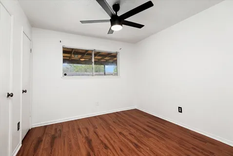 a view of a room with wooden floor and a ceiling fan