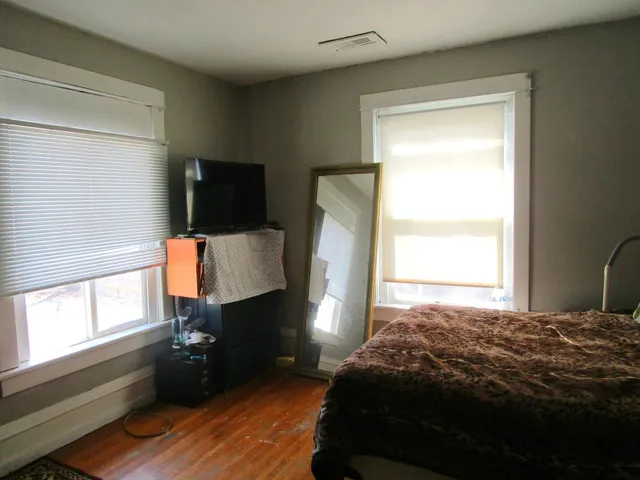 a bedroom with a bed window and wooden floor