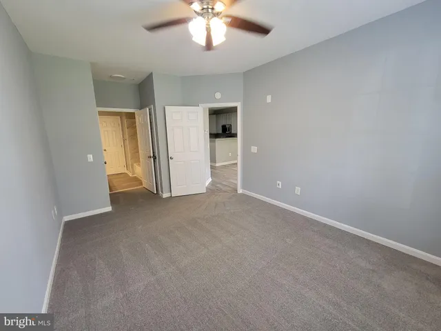 an empty room with a chandelier fan and windows