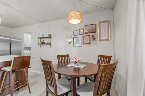 a kitchen with stainless steel appliances granite countertop a table chairs and a refrigerator