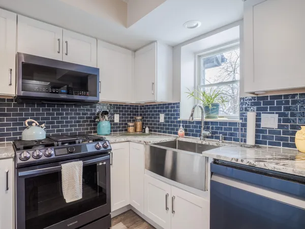 a kitchen with granite countertop a stove sink and cabinets