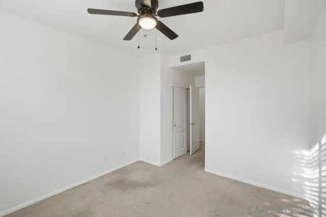 an empty room with a window and a fan