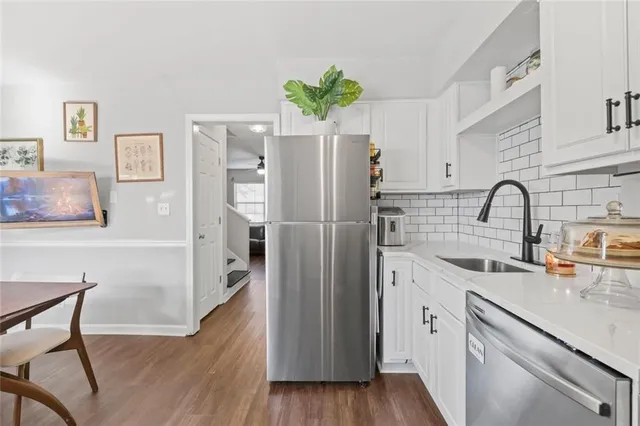 a kitchen with stainless steel appliances a refrigerator a sink a stove and white cabinets