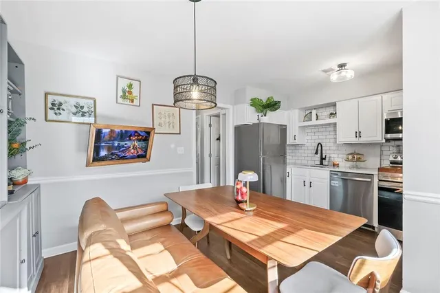 a kitchen with stainless steel appliances kitchen island granite countertop a refrigerator a stove a sink dishwasher a dining table and chairs with wooden floor