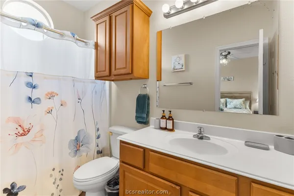 a bathroom with a granite countertop sink mirror vanity and toilet
