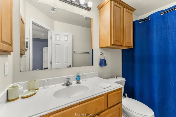a bathroom with a granite countertop sink mirror vanity and toilet