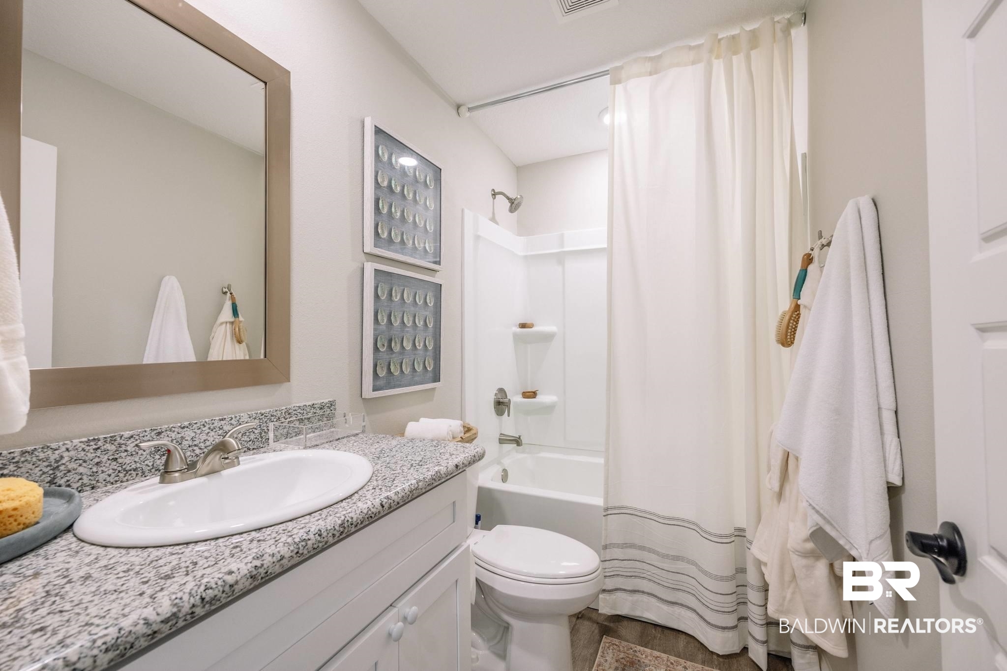 12918 Flanagan Street Elberta, AL 36530 - Photo 17 of 33 Bathroom featuring a granite countertop vanity with an undermount sink, a framed mirror, white cabinetry, a full bathtub with a shower, and a white shower curtain