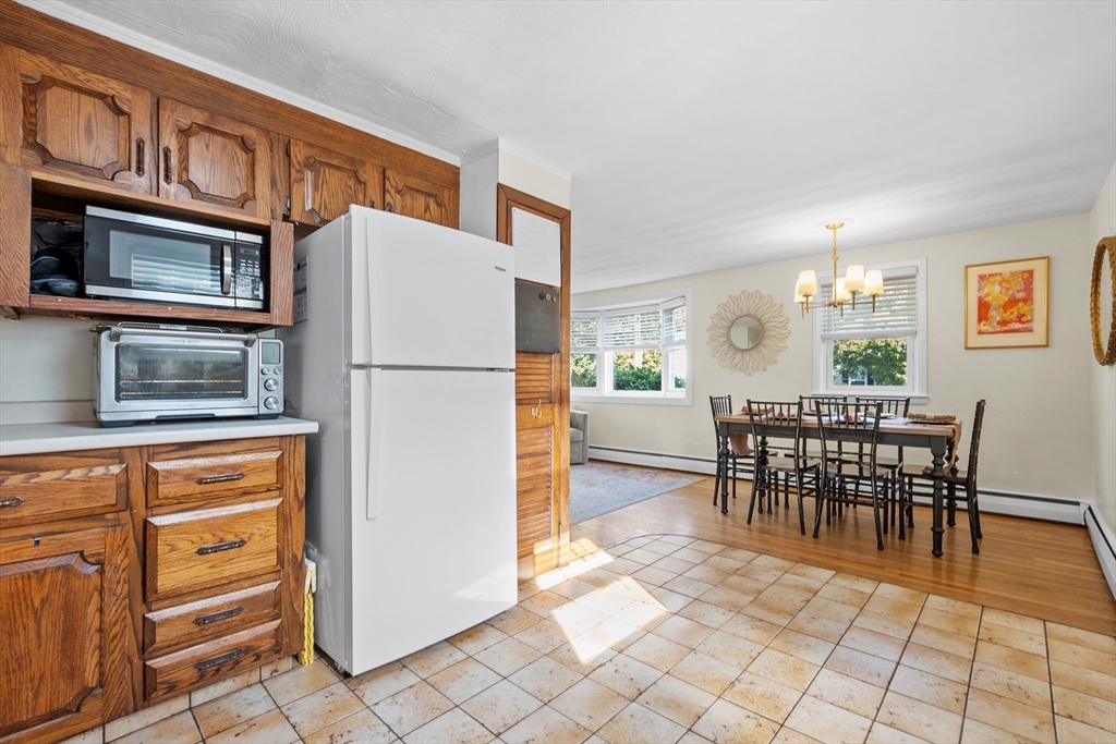 2 Lodge Road Natick, MA 01760 - Photo 9 of 36 a kitchen with stainless steel appliances granite countertop a refrigerator a stove a dining table and chairs with wooden floor