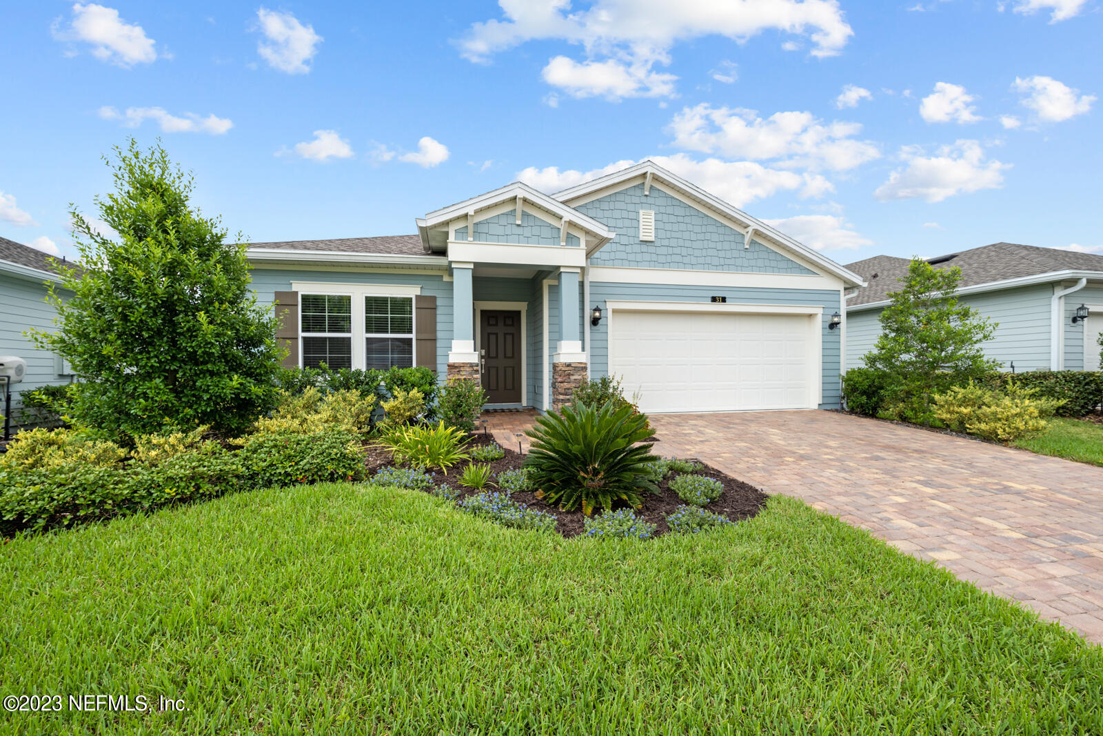 a view of a white house next to a yard with plants and trees